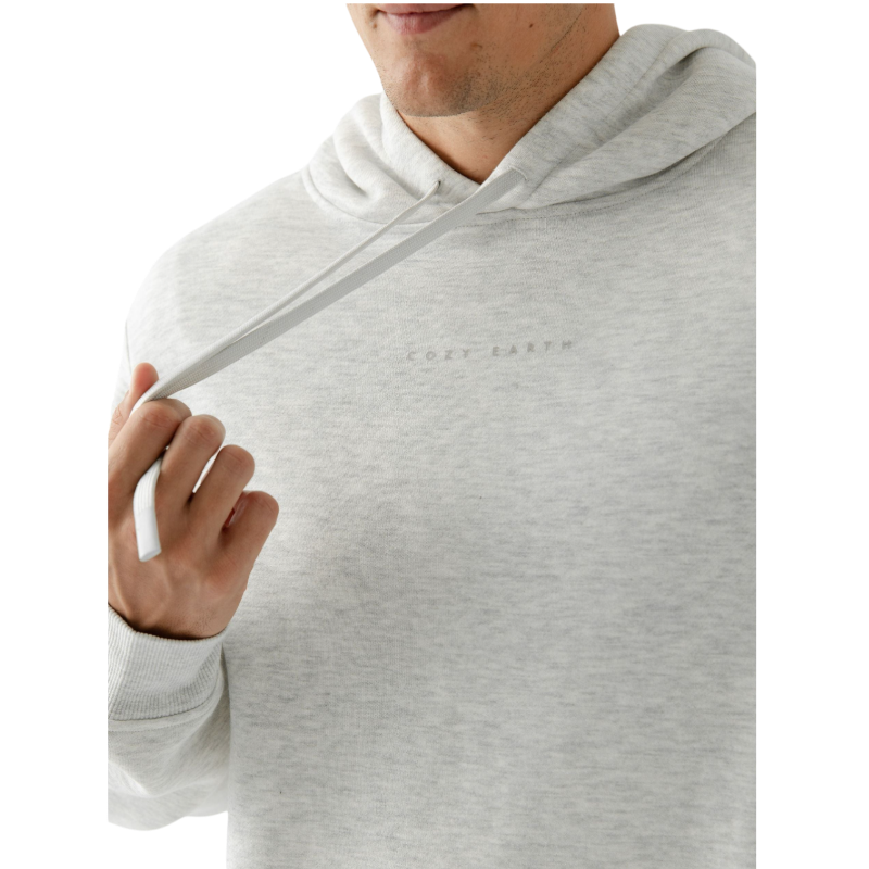 A person with curly hair is wearing a Cozy Earth Men's CityScape Hoodie in dark green and standing against a plain white background, with their hands together. |Color:Spruce