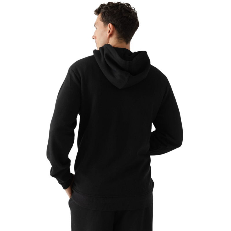 A person with curly hair is wearing a Cozy Earth Men's CityScape Hoodie in dark green and standing against a plain white background, with their hands together. |Color:Spruce