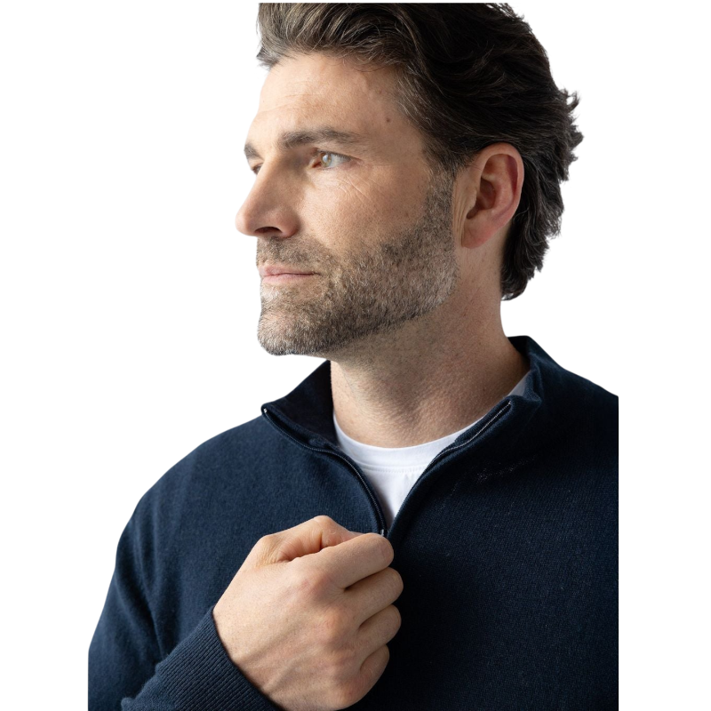 A man with dark hair and a short beard is wearing a navy blue Men's Quarter Zip Sweater from Cozy Earth paired with beige pants. He stands with his hands in his pockets against a plain white background, looking to his right with a slight smile. |Color:Eclipse