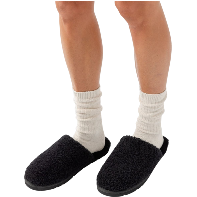Close-up of a person's lower legs wearing white crew socks and Cozy Earth's Puffy Sheep Slipper, which are black and fuzzy. The background is plain white. |Color:Black Sheep