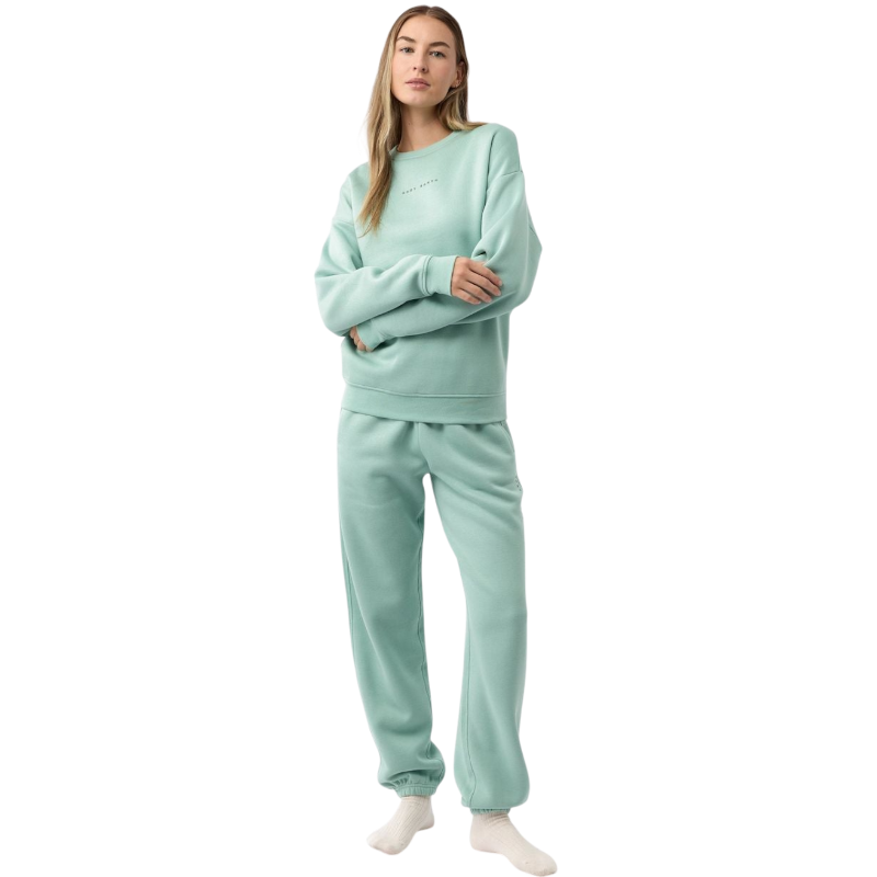 A person with curly hair models the Cozy Earth Women's CityScape Crewneck and matching pants in light pink against a plain white backdrop. |Color:Peony