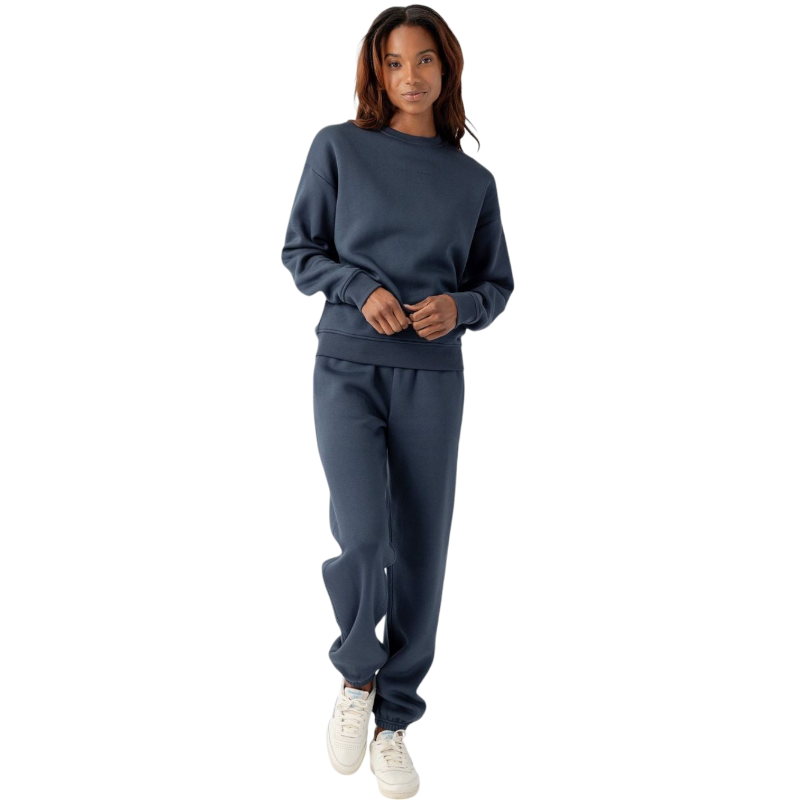 A person with curly hair models the Cozy Earth Women's CityScape Crewneck and matching pants in light pink against a plain white backdrop. |Color:Peony