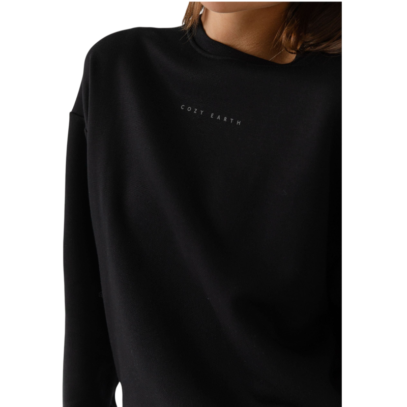 A person with curly hair models the Cozy Earth Women's CityScape Crewneck and matching pants in light pink against a plain white backdrop. |Color:Peony