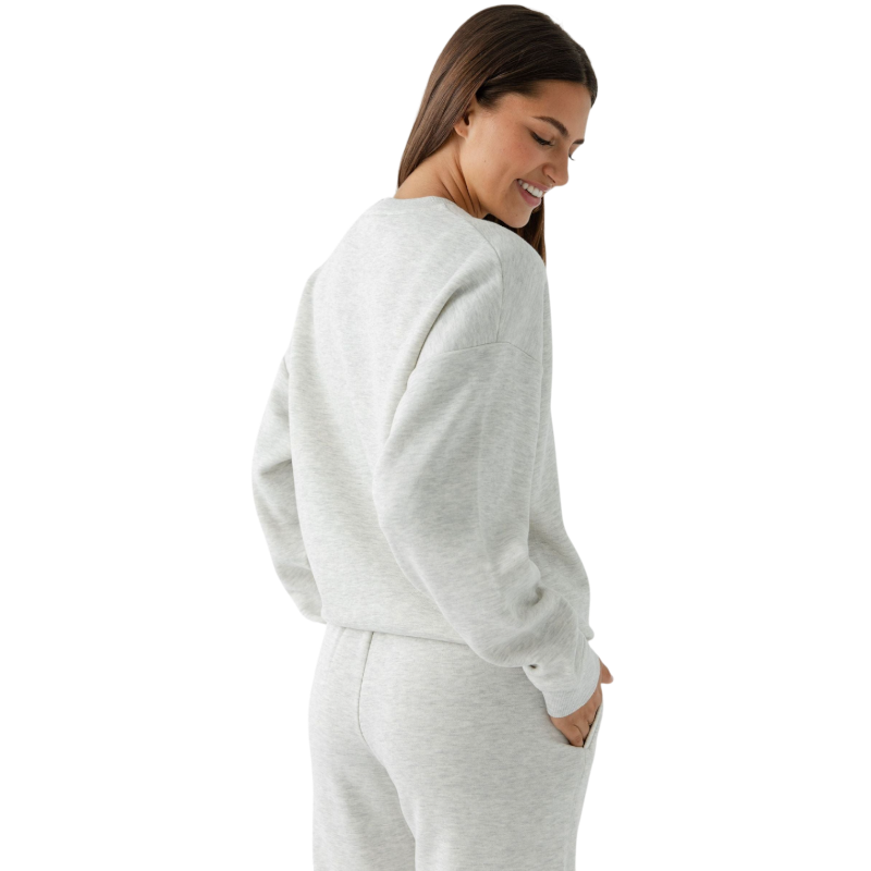 A person with curly hair models the Cozy Earth Women's CityScape Crewneck and matching pants in light pink against a plain white backdrop. |Color:Peony