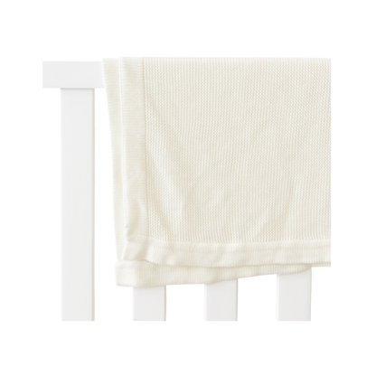 Ivory Cloud Knit Baby Blanket draped over crib |Color:Ivory