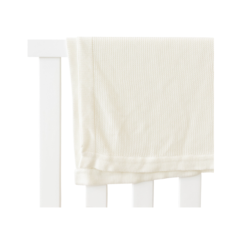 Ivory Cloud Knit Baby Blanket draped over crib |Color:Ivory