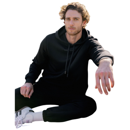 A person with curly hair is wearing a Cozy Earth Men's CityScape Hoodie in dark green and standing against a plain white background, with their hands together. |Color:Spruce