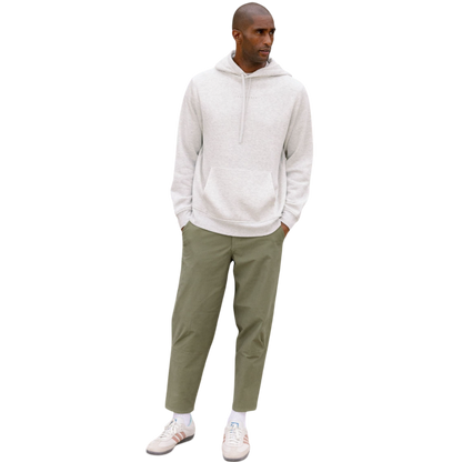 A person with curly hair is wearing a Cozy Earth Men's CityScape Hoodie in dark green and standing against a plain white background, with their hands together. |Color:Spruce