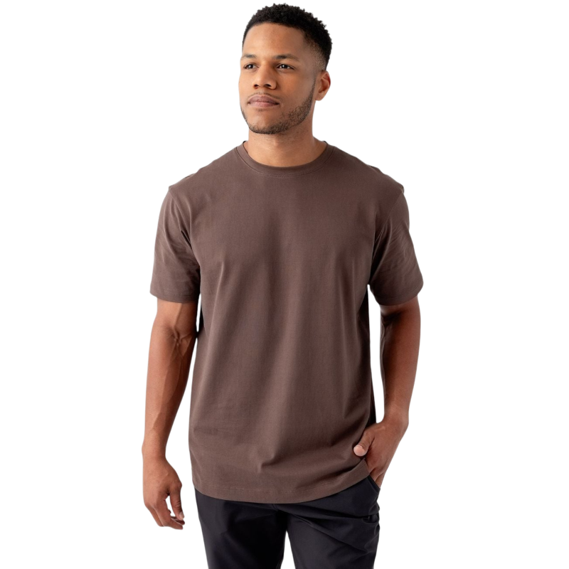 A man with short black hair and a short beard is wearing a brown Men's All Day Tee from Cozy Earth along with black pants. He stands facing slightly to the left with a hand in his pocket, against a plain white background. |Color:Cacao