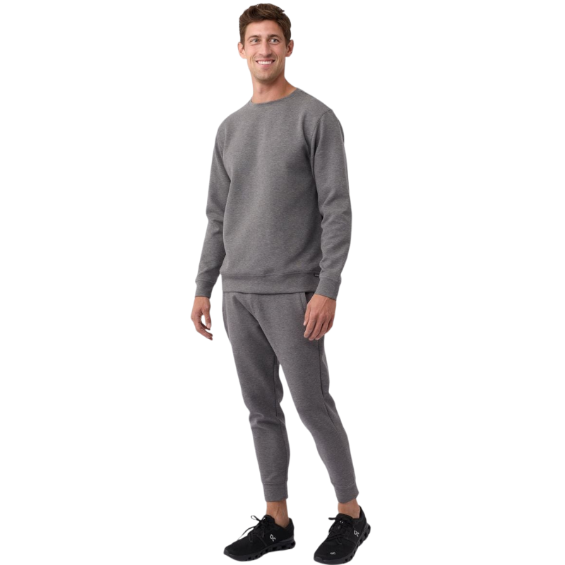 A man is wearing the Men's StretchTech Crewneck sweatshirt from Cozy Earth, paired with matching sweatpants. He stands against a plain white background with short brown hair, looking forward with a neutral expression. |Color:Coal Heather