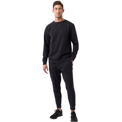 A man is wearing the Men's StretchTech Crewneck sweatshirt from Cozy Earth, paired with matching sweatpants. He stands against a plain white background with short brown hair, looking forward with a neutral expression. |Color:Coal Heather