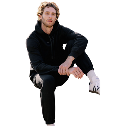 A person with curly hair is wearing a Cozy Earth Men's CityScape Hoodie in dark green and standing against a plain white background, with their hands together. |Color:Spruce