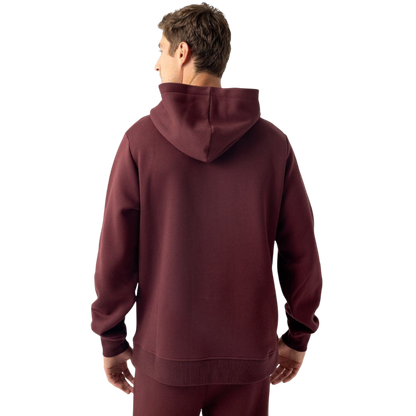 A person with curly hair is wearing a Cozy Earth Men's CityScape Hoodie in dark green and standing against a plain white background, with their hands together. |Color:Spruce