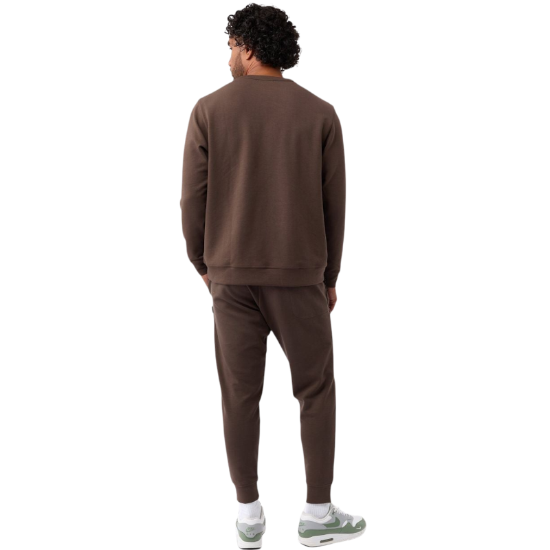 A man is wearing the Men's StretchTech Crewneck sweatshirt from Cozy Earth, paired with matching sweatpants. He stands against a plain white background with short brown hair, looking forward with a neutral expression. |Color:Coal Heather