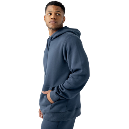 A person with curly hair is wearing a Cozy Earth Men's CityScape Hoodie in dark green and standing against a plain white background, with their hands together. |Color:Spruce