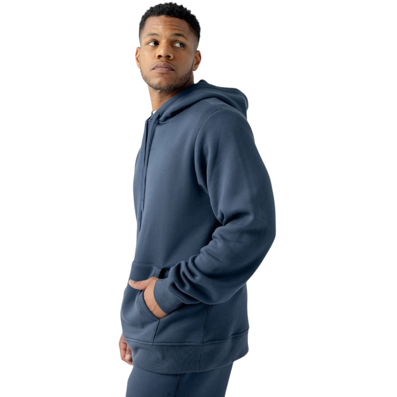 A person with curly hair is wearing a Cozy Earth Men's CityScape Hoodie in dark green and standing against a plain white background, with their hands together. |Color:Spruce