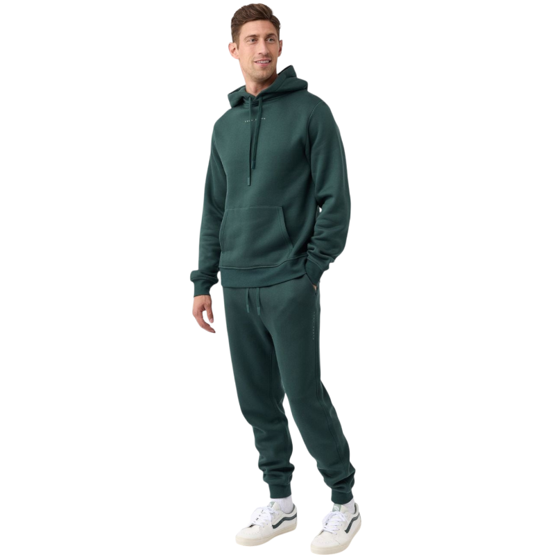 A person with curly hair is wearing a Cozy Earth Men's CityScape Hoodie in dark green and standing against a plain white background, with their hands together. |Color:Spruce