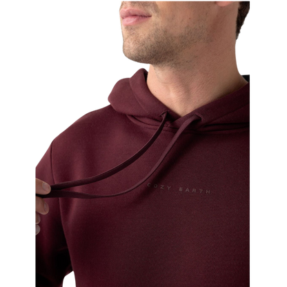 A person with curly hair is wearing a Cozy Earth Men's CityScape Hoodie in dark green and standing against a plain white background, with their hands together. |Color:Spruce