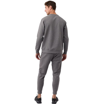 A man is wearing the Men's StretchTech Crewneck sweatshirt from Cozy Earth, paired with matching sweatpants. He stands against a plain white background with short brown hair, looking forward with a neutral expression. |Color:Coal Heather