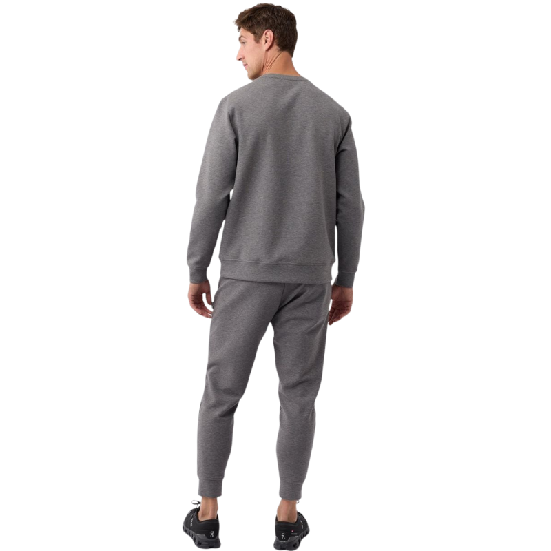 A man is wearing the Men's StretchTech Crewneck sweatshirt from Cozy Earth, paired with matching sweatpants. He stands against a plain white background with short brown hair, looking forward with a neutral expression. |Color:Coal Heather