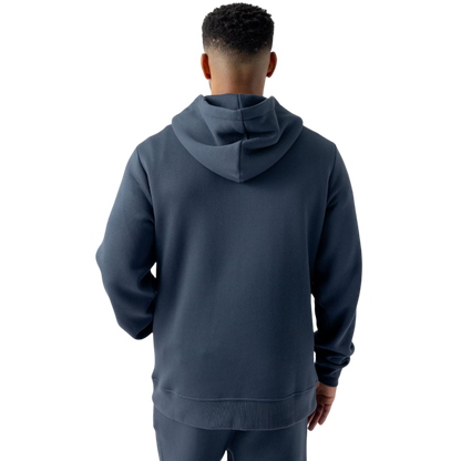 A person with curly hair is wearing a Cozy Earth Men's CityScape Hoodie in dark green and standing against a plain white background, with their hands together. |Color:Spruce