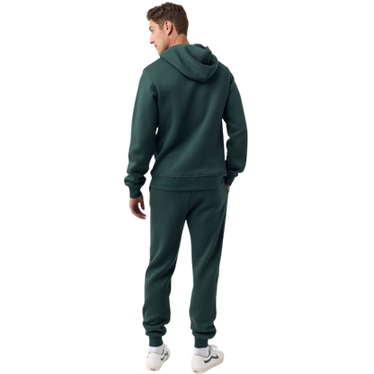 A person with curly hair is wearing a Cozy Earth Men's CityScape Hoodie in dark green and standing against a plain white background, with their hands together. |Color:Spruce