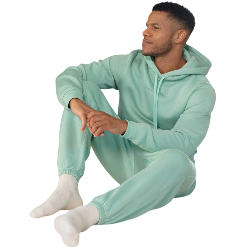 A person with curly hair is wearing a Cozy Earth Men's CityScape Hoodie in dark green and standing against a plain white background, with their hands together. |Color:Spruce