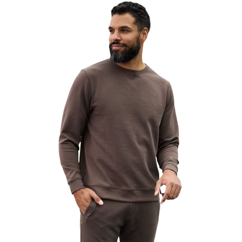A man is wearing the Men's StretchTech Crewneck sweatshirt from Cozy Earth, paired with matching sweatpants. He stands against a plain white background with short brown hair, looking forward with a neutral expression. |Color:Coal Heather