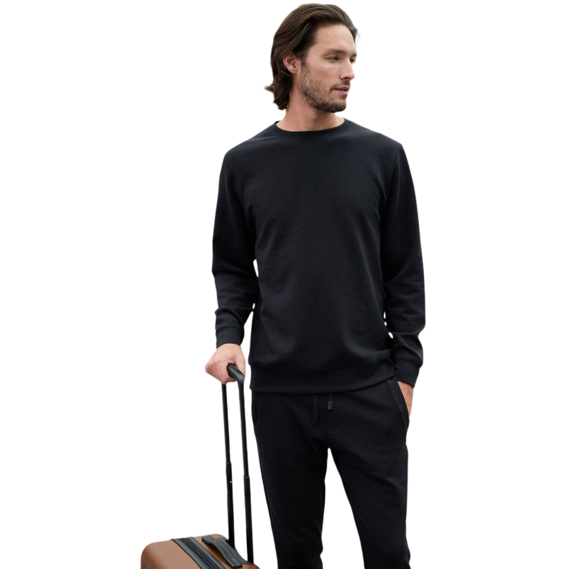 A man is wearing the Men's StretchTech Crewneck sweatshirt from Cozy Earth, paired with matching sweatpants. He stands against a plain white background with short brown hair, looking forward with a neutral expression. |Color:Coal Heather