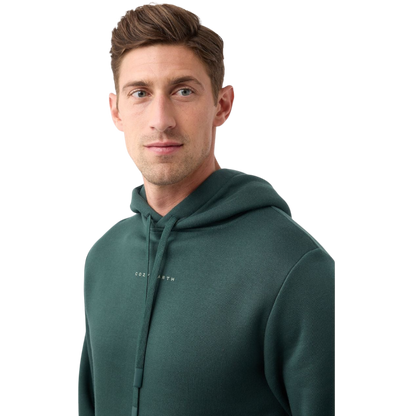 A person with curly hair is wearing a Cozy Earth Men's CityScape Hoodie in dark green and standing against a plain white background, with their hands together. |Color:Spruce