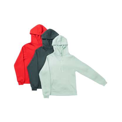 A person with curly hair is wearing a Cozy Earth Men's CityScape Hoodie in dark green and standing against a plain white background, with their hands together. |Color:Spruce