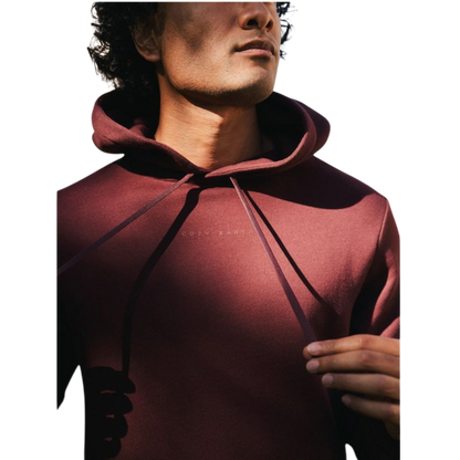 A person with curly hair is wearing a Cozy Earth Men's CityScape Hoodie in dark green and standing against a plain white background, with their hands together. |Color:Spruce