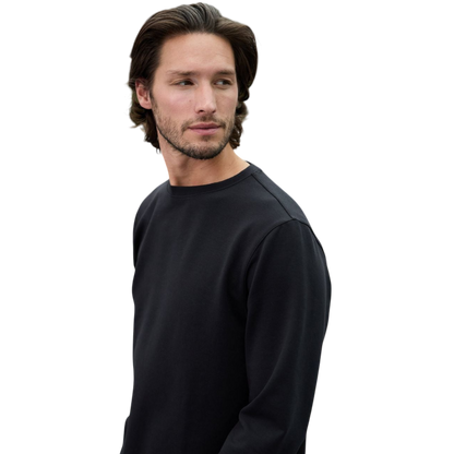 A man is wearing the Men's StretchTech Crewneck sweatshirt from Cozy Earth, paired with matching sweatpants. He stands against a plain white background with short brown hair, looking forward with a neutral expression. |Color:Coal Heather