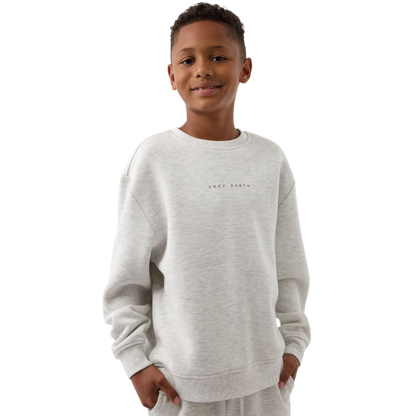 A young boy with blond hair is wearing the Cozy Earth Kid's CityScape Crewneck sweatshirt along with matching pants. He is standing, smiling, and looking slightly to the side against a plain white background. |Color:Eclipse