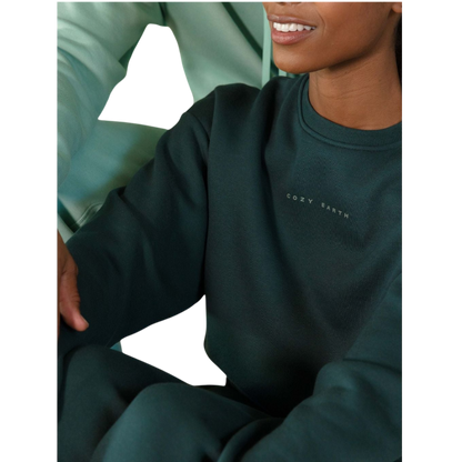 A young boy with blond hair is wearing the Cozy Earth Kid's CityScape Crewneck sweatshirt along with matching pants. He is standing, smiling, and looking slightly to the side against a plain white background. |Color:Eclipse