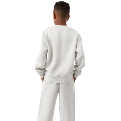 A young boy with blond hair is wearing the Cozy Earth Kid's CityScape Crewneck sweatshirt along with matching pants. He is standing, smiling, and looking slightly to the side against a plain white background. |Color:Eclipse