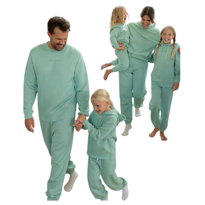 A young boy with blond hair is wearing the Cozy Earth Kid's CityScape Crewneck sweatshirt along with matching pants. He is standing, smiling, and looking slightly to the side against a plain white background. |Color:Eclipse