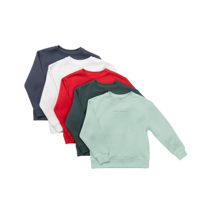 A young boy with blond hair is wearing the Cozy Earth Kid's CityScape Crewneck sweatshirt along with matching pants. He is standing, smiling, and looking slightly to the side against a plain white background. |Color:Eclipse