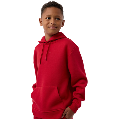 A child wearing a Kid's CityScape Hoodie by Cozy Earth smiles while looking to the side. The red hoodie features a front pocket against a plain white background. |Color:Crimson