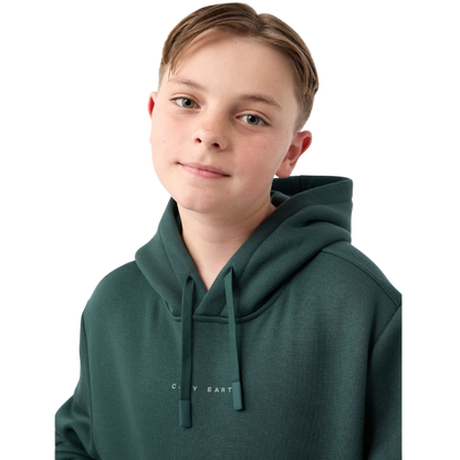A young child with long blonde hair smiles while wearing a navy blue Kid's CityScape Hoodie by Cozy Earth and matching pants. She has two hair ties, one pink and one blue. The background is plain white. |Color:Eclipse