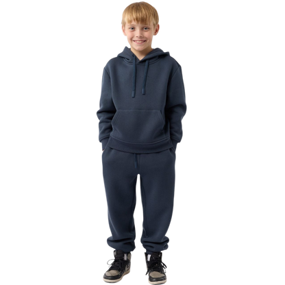 A young child with long blonde hair smiles while wearing a navy blue Kid's CityScape Hoodie by Cozy Earth and matching pants. She has two hair ties, one pink and one blue. The background is plain white. |Color:Eclipse