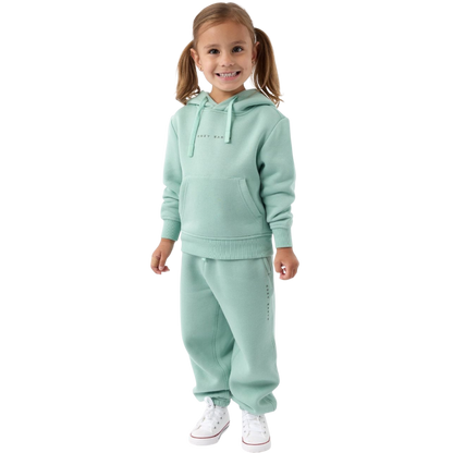A young child with long blonde hair smiles while wearing a navy blue Kid's CityScape Hoodie by Cozy Earth and matching pants. She has two hair ties, one pink and one blue. The background is plain white. |Color:Eclipse