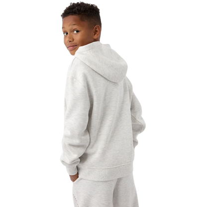 A young child with long blonde hair smiles while wearing a navy blue Kid's CityScape Hoodie by Cozy Earth and matching pants. She has two hair ties, one pink and one blue. The background is plain white. |Color:Eclipse