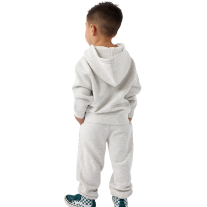 A young child with long blonde hair smiles while wearing a navy blue Kid's CityScape Hoodie by Cozy Earth and matching pants. She has two hair ties, one pink and one blue. The background is plain white. |Color:Eclipse