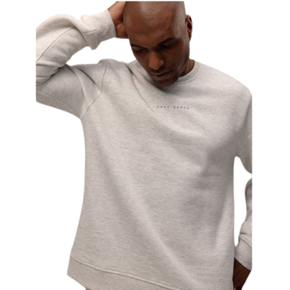 A man with short brown hair is wearing a dark green Men's CityScape Crewneck from Cozy Earth, featuring the words "COLD EARTH" printed on it. He is gazing slightly to the side against a plain white background. |Color:Spruce