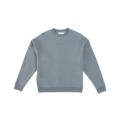 A man with short brown hair is wearing a dark green Men's CityScape Crewneck from Cozy Earth, featuring the words "COLD EARTH" printed on it. He is gazing slightly to the side against a plain white background. |Color:Spruce