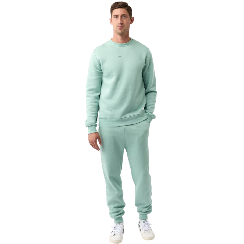 A man with short brown hair is wearing a dark green Men's CityScape Crewneck from Cozy Earth, featuring the words "COLD EARTH" printed on it. He is gazing slightly to the side against a plain white background. |Color:Spruce