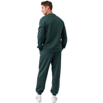 A man with short brown hair is wearing a dark green Men's CityScape Crewneck from Cozy Earth, featuring the words "COLD EARTH" printed on it. He is gazing slightly to the side against a plain white background. |Color:Spruce