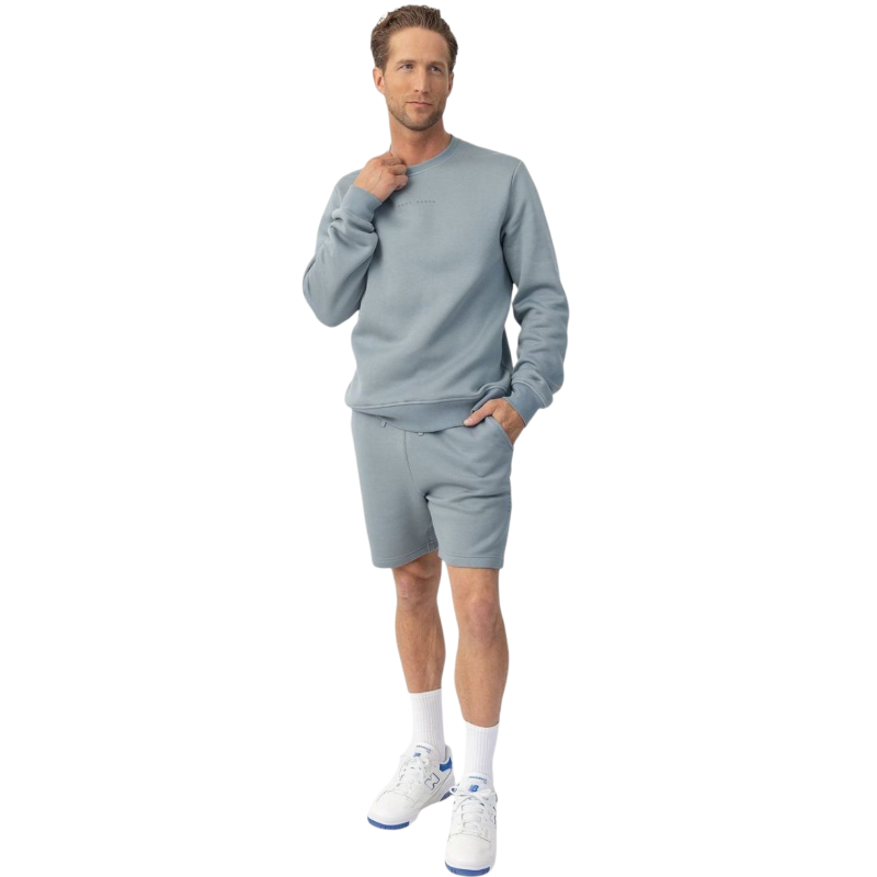 A man with short brown hair is wearing a dark green Men's CityScape Crewneck from Cozy Earth, featuring the words "COLD EARTH" printed on it. He is gazing slightly to the side against a plain white background. |Color:Spruce