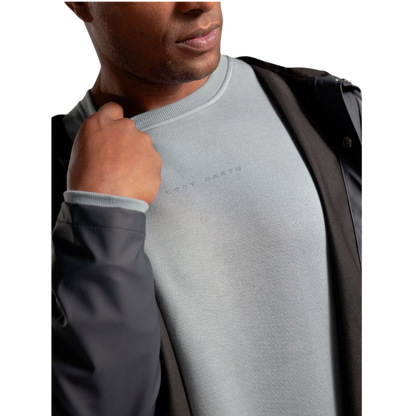 A man with short brown hair is wearing a dark green Men's CityScape Crewneck from Cozy Earth, featuring the words "COLD EARTH" printed on it. He is gazing slightly to the side against a plain white background. |Color:Spruce
